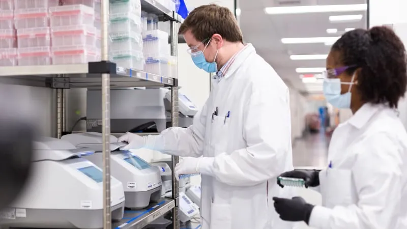 Учени на Moderna работят с PCR апаратура в лабораторията на компанията